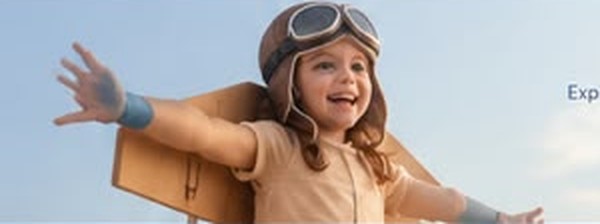 Child in a cardboard airplane costume with arms spread wide